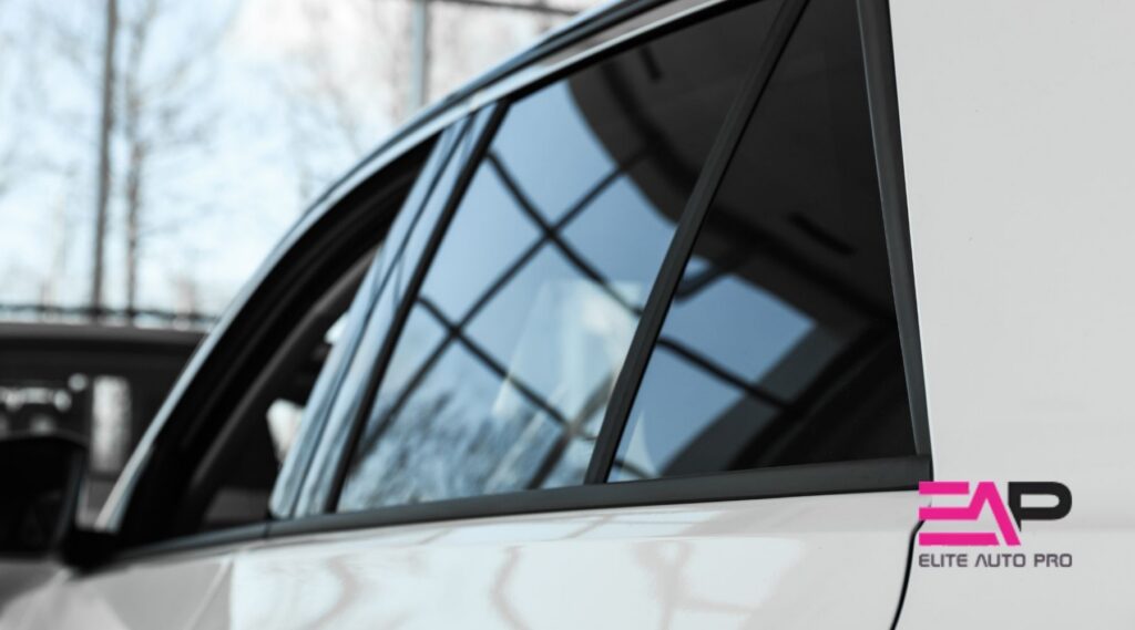 White car with dark window tint parked indoors, featuring the Elite Auto PRO logo