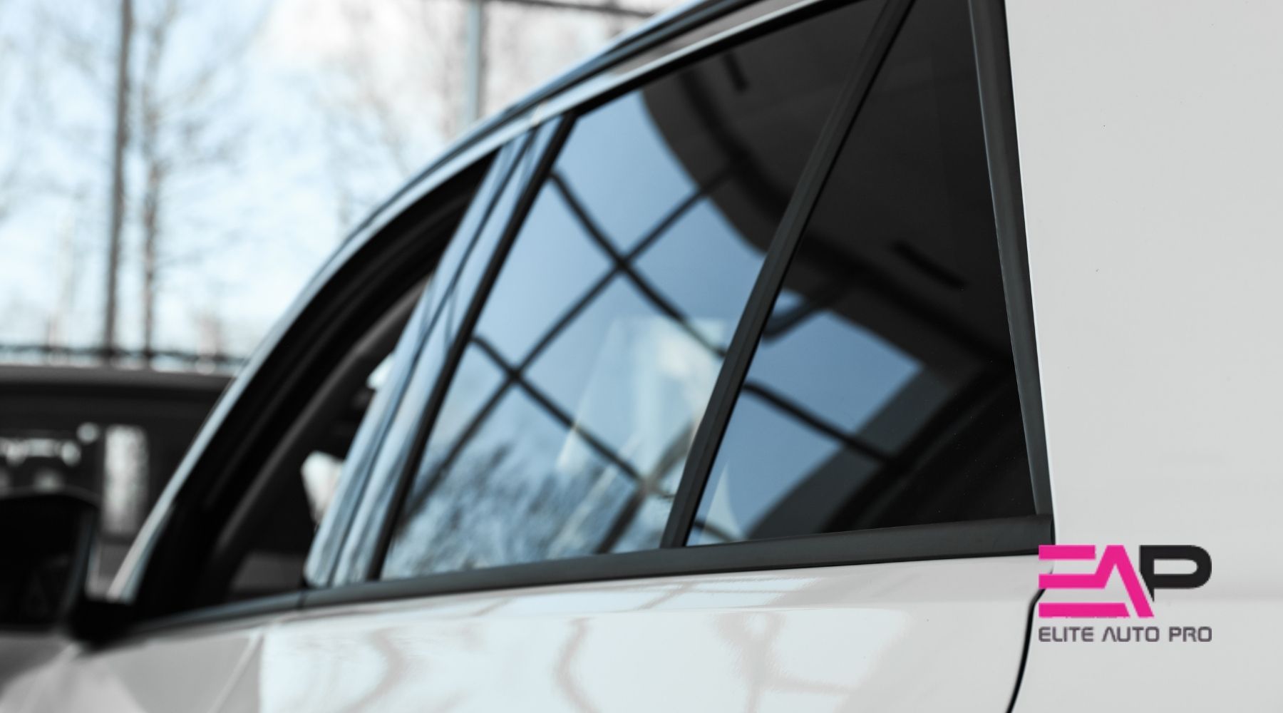 White car with dark window tint parked indoors, featuring the Elite Auto PRO logo