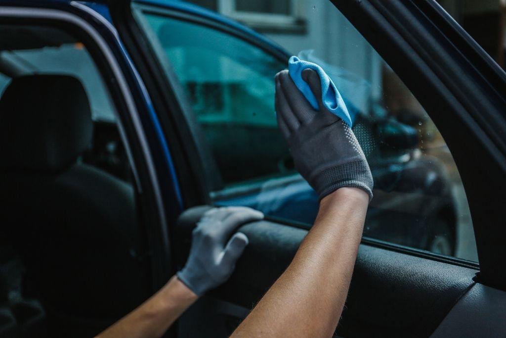 Technician cleaning a car window before window tint installation