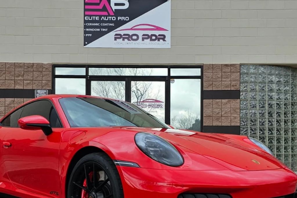 Red Porsche parked outside Elite Auto PRO with dark window tint installed